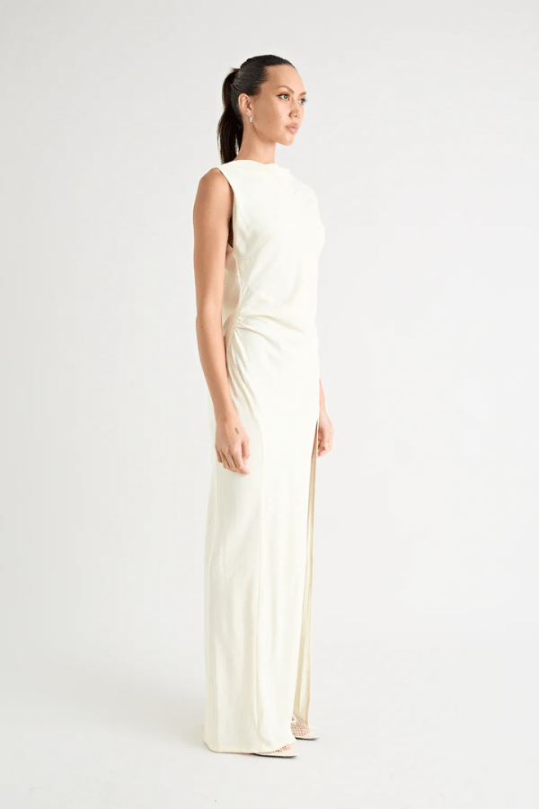 Matia Gown Butter by Pfeiffer – A timeless maxi with a boat neckline, low back, and adjustable strap. Perfect for elegant events and special occasions.
