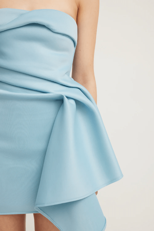 Nevie Dress Powder Blue by Tojhà – A modern mini gown in lightweight neoprene, featuring structured folds and a graceful waterfall drape, perfect for stylish evenings.