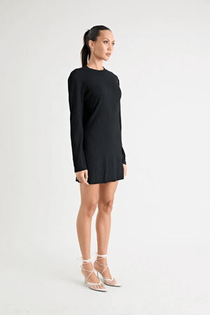 Fairbank Rib Dress Black by Pfeiffer – A trendy, comfortable ribbed bamboo dress with high raw-edge neckline, full sleeves, and versatile two-part back design. Perfect for chic casual wear or layering in cooler seasons.