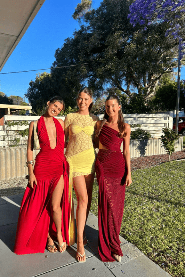 Dakota Pure Red by Deconduarte – Trendy fluid jersey dress with elastic neckline, fitted belt skirt, side slit, and lettuce-edge hem, perfect for confident, carefree occasions.