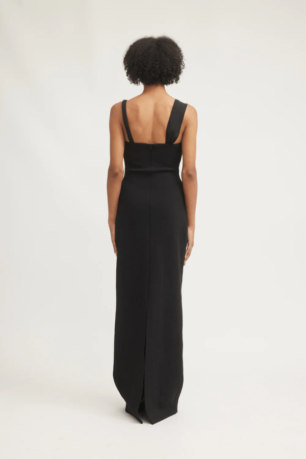 Madeleine Dress Black by Tojhà – A viral double-bonded crepe maxi with asymmetric straps, curved cut-out, and layered mesh, perfect for elegant evening events.