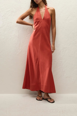 Amara Midi Dress by Faithfull the Brand — a dusty tomato linen halter dress with an open back and flowing bias-cut skirt, perfect for warm vacations.