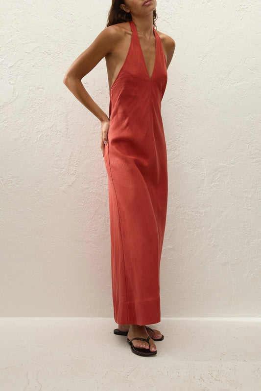 Amara Midi Dress by Faithfull the Brand — a dusty tomato linen halter dress with an open back and flowing bias-cut skirt, perfect for warm vacations.