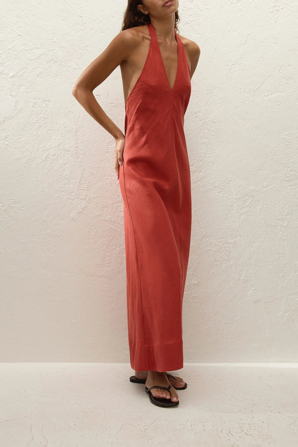 Amara Midi Dress by Faithfull the Brand — a dusty tomato linen halter dress with an open back and flowing bias-cut skirt, perfect for warm vacations.