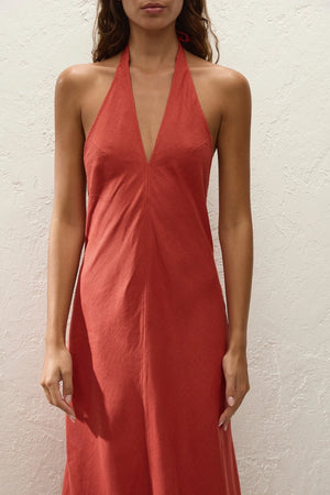 Amara Midi Dress by Faithfull the Brand — a dusty tomato linen halter dress with an open back and flowing bias-cut skirt, perfect for warm vacations.