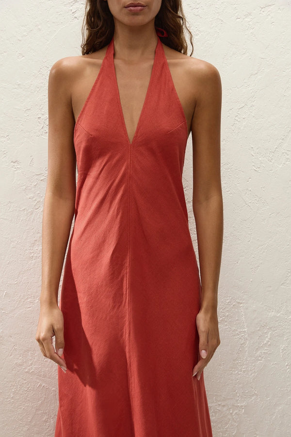 Amara Midi Dress by Faithfull the Brand — a dusty tomato linen halter dress with an open back and flowing bias-cut skirt, perfect for warm vacations.