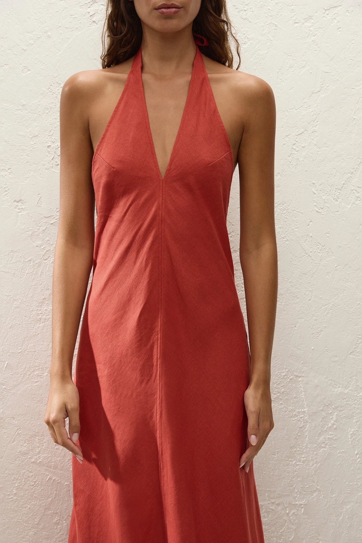 Amara Midi Dress by Faithfull the Brand — a dusty tomato linen halter dress with an open back and flowing bias-cut skirt, perfect for warm vacations.
