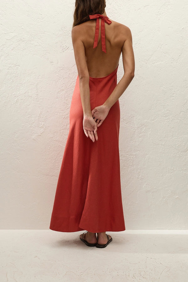 Amara Midi Dress by Faithfull the Brand — a dusty tomato linen halter dress with an open back and flowing bias-cut skirt, perfect for warm vacations.