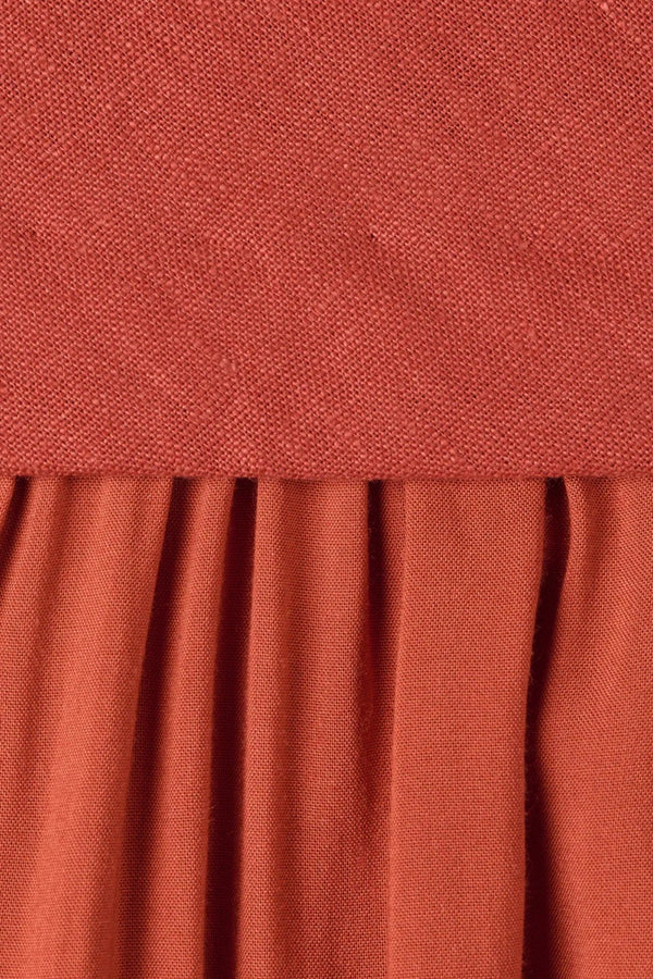Amara Midi Dress by Faithfull the Brand — a dusty tomato linen halter dress with an open back and flowing bias-cut skirt, perfect for warm vacations.