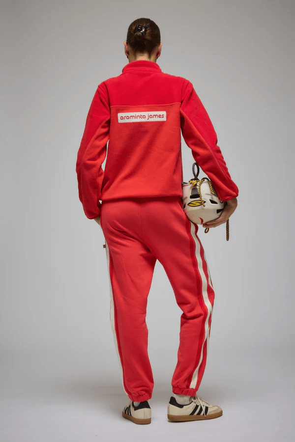 Bisous Trackpant Coral by Araminta James, features a relaxed fit with tapered leg, soft brushed fleece fabric, elasticized waistband with drawcord, side pockets, elastic cuffs, and contrast side trims.