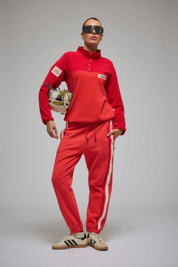 Bisous Trackpant Coral by Araminta James, features a relaxed fit with tapered leg, soft brushed fleece fabric, elasticized waistband with drawcord, side pockets, elastic cuffs, and contrast side trims.