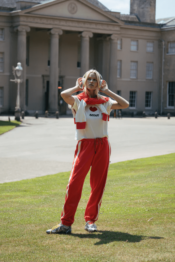 Bisous Trackpant Coral by Araminta James, features a relaxed fit with tapered leg, soft brushed fleece fabric, elasticized waistband with drawcord, side pockets, elastic cuffs, and contrast side trims.