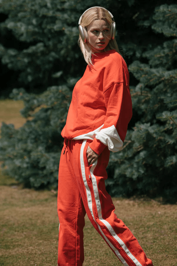 Bisous Trackpant Coral by Araminta James, features a relaxed fit with tapered leg, soft brushed fleece fabric, elasticized waistband with drawcord, side pockets, elastic cuffs, and contrast side trims.
