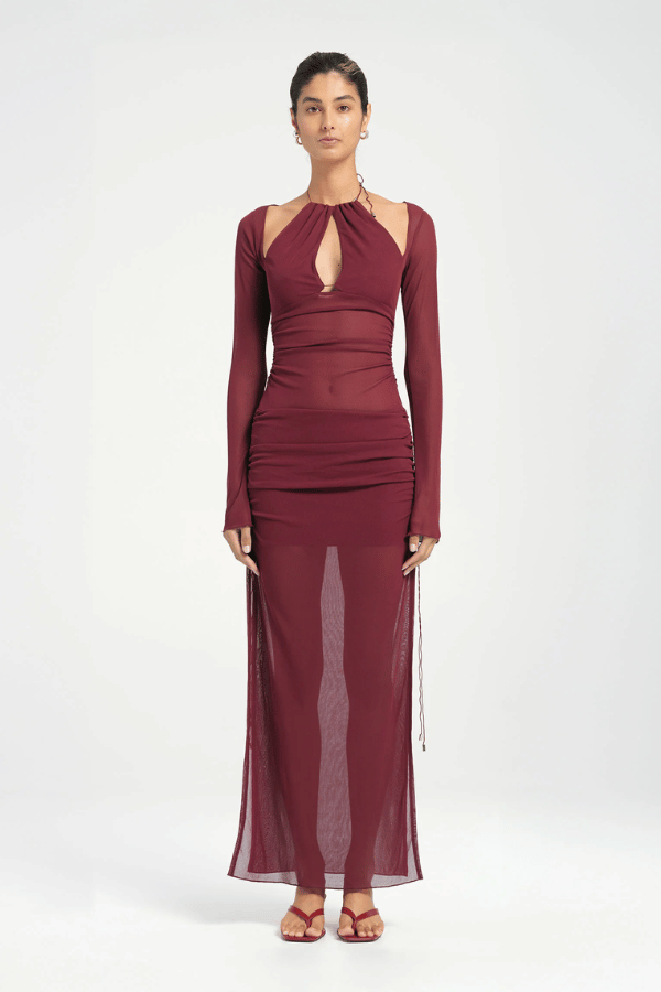 Ari Cutaway Dress Berry by Benni – A trendy maxi with bold geometric cut-outs and sleek long sleeves, perfect for glamorous evenings and statement occasions.