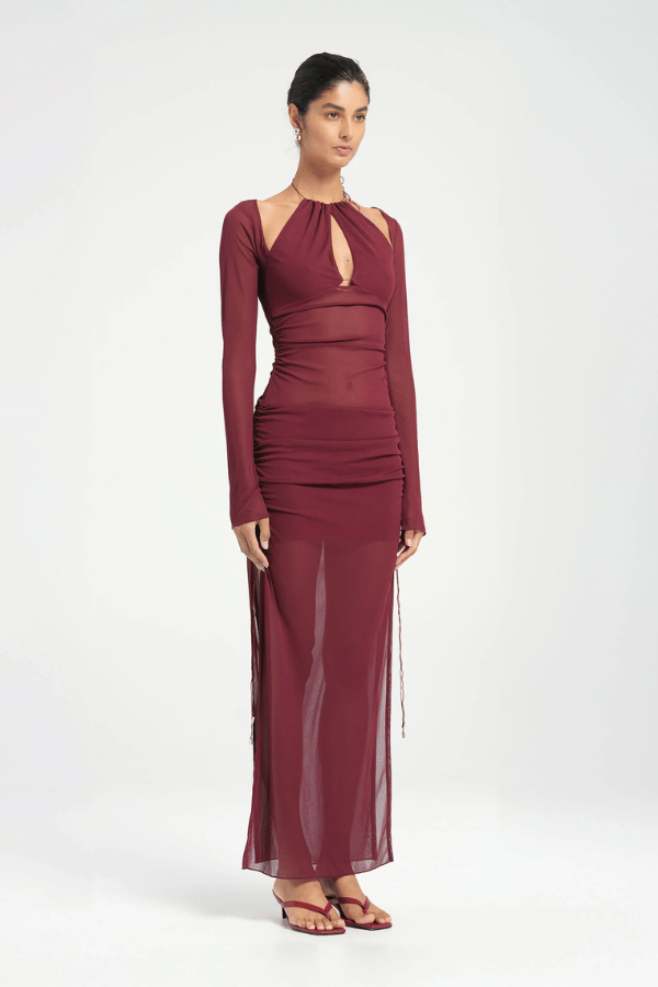Ari Cutaway Dress Berry by Benni – A trendy maxi with bold geometric cut-outs and sleek long sleeves, perfect for glamorous evenings and statement occasions.