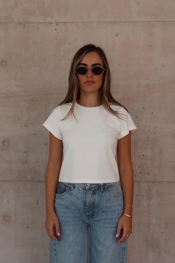 Claudia Baby Tee White by Sneaky Link – A relaxed, cropped tee crafted from a soft viscose-spandex blend for comfort and stretch. Perfect casual chic with short sleeves.