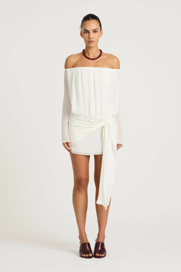 Bernie Mini Dress by Benni, white off-shoulder mini with long sleeves, draped front, waist tie and sheer feminine silhouette.
