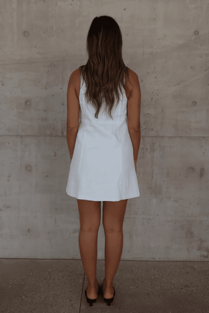 Mia Mini Dress White by Sneaky Link – A trendy, breathable linen dress with a high scoop neckline and button front, perfect for effortless summer days.