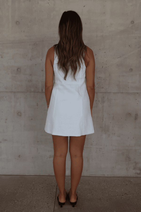 Mia Mini Dress White by Sneaky Link – A trendy, breathable linen dress with a high scoop neckline and button front, perfect for effortless summer days.