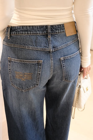 Elisha Baggy Jean Indigo by Sneaky Link, relaxed mid-rise baggy jeans in 100% cotton with branded details. Runs big; size down if unsure.