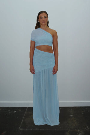 Tiana Dress Baby Blue by DŽO – Trendy one-shoulder sheer mesh maxi with asymmetrical draping, waist cutout, and pleated skirt, perfect for elegant day-to-evening occasions.
