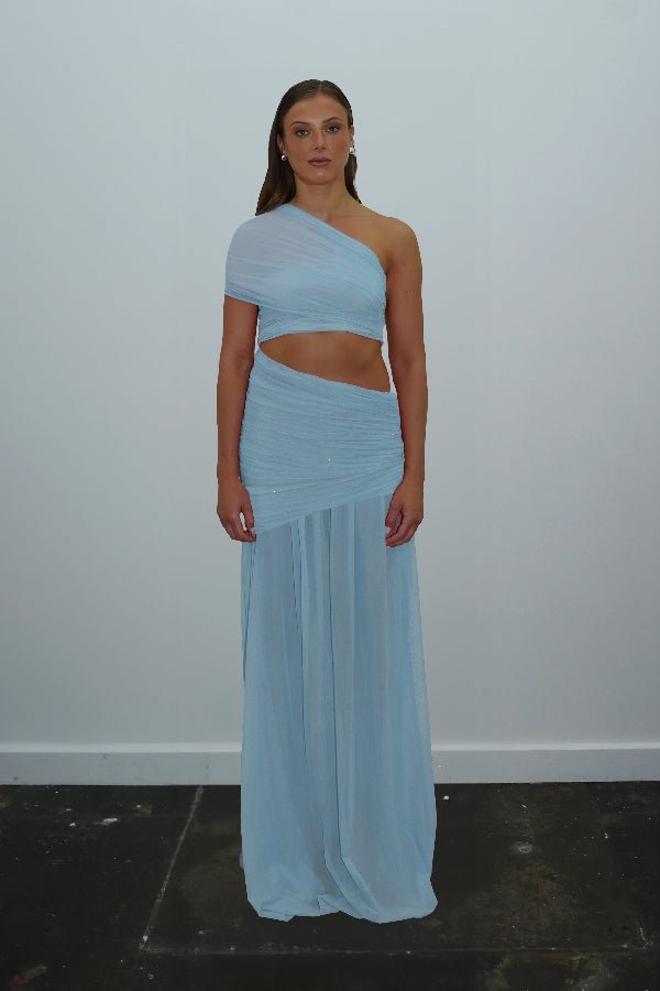 Tiana Dress Baby Blue by DŽO – Trendy one-shoulder sheer mesh maxi with asymmetrical draping, waist cutout, and pleated skirt, perfect for elegant day-to-evening occasions.