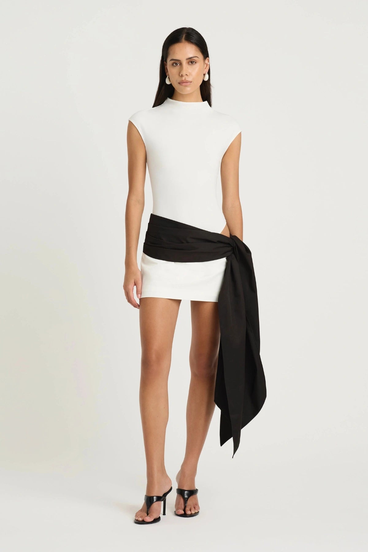 Dakota Mini Dress by Benni, a white mini with cap sleeves and asymmetric tie detail. Perfect for polished summer days or events.