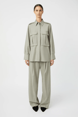 Drew Pant Mottled Stone by Camilla and Marc, tailored low-rise pant with front pleats, fishtail waistband, single arrow belt loops, and back jet pockets with button detail. Crafted in a wool-poly blend with permanent press finish.