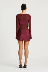 Elvira Mini Dress in Plum by Benni, a sheer stretch mesh mini with long sleeves, satin bralette panel, and draped cowl skirt.