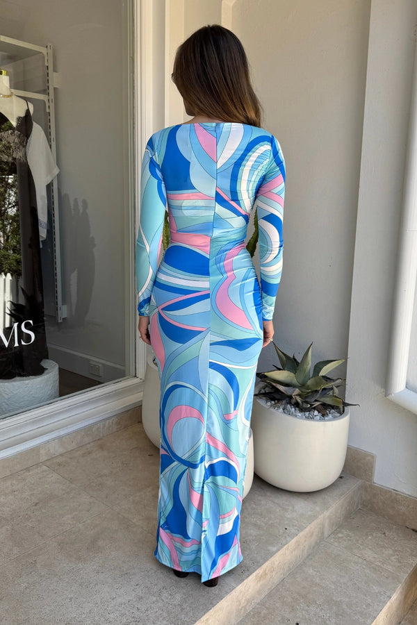 ‘Empress’ Maxi Dress in Dolce Blue by Cin Cin, featuring side ruching, boatneck neckline, and a flowing longline silhouette in a vibrant seventies-inspired print.
