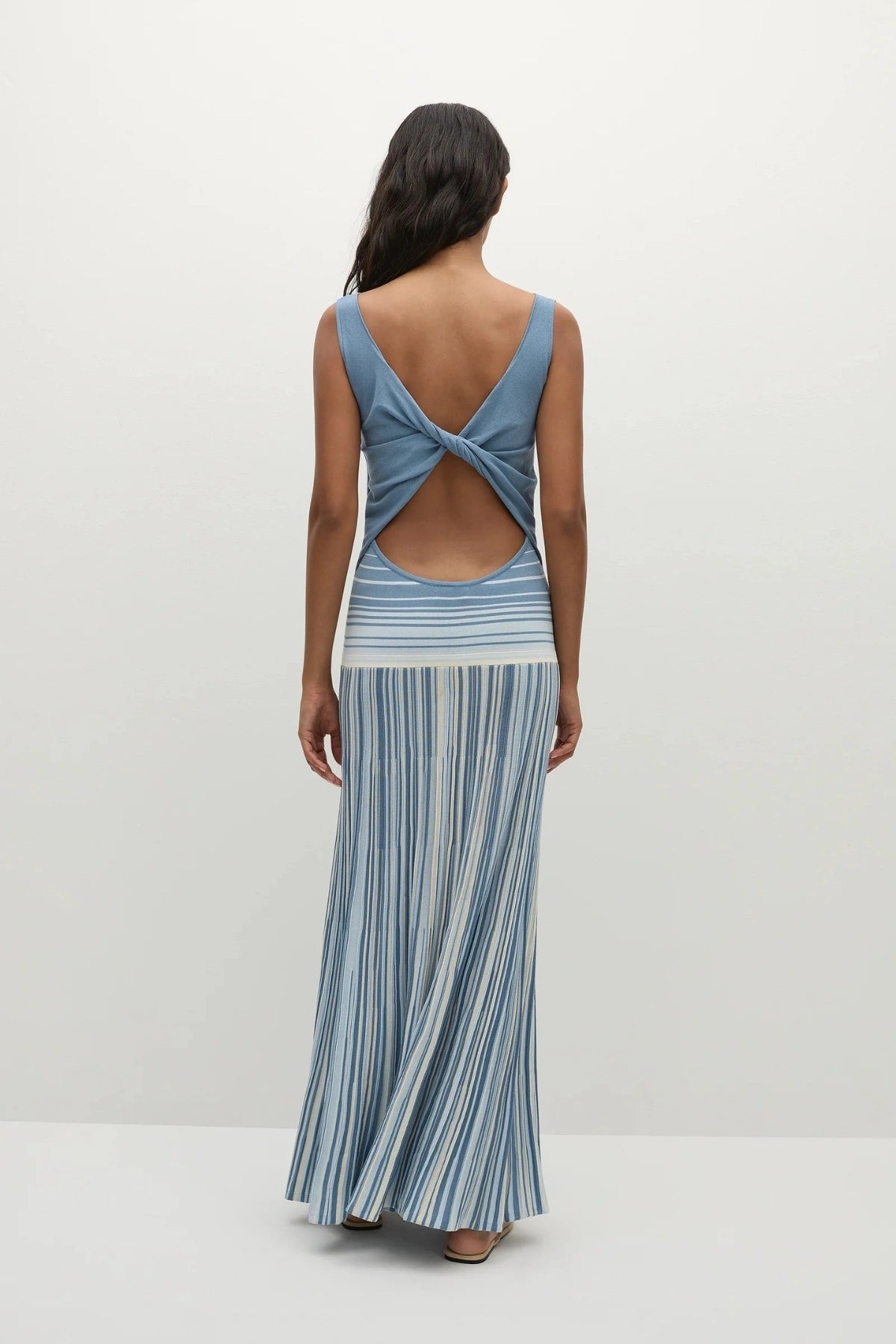 Faithfull the Brand Xyla Maxi Dress in Accordion Stripe Mineral Blue with boat neckline, twist knot back and flared A-line skirt.