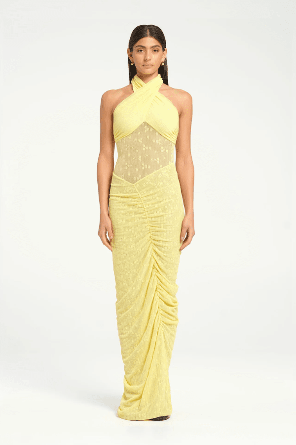 Hudson Lace Maxi Dress Butter by Benni, elegant stretch lace dress with twist halter neck, ruched seams, and sheer waist panel for a bold evening look.