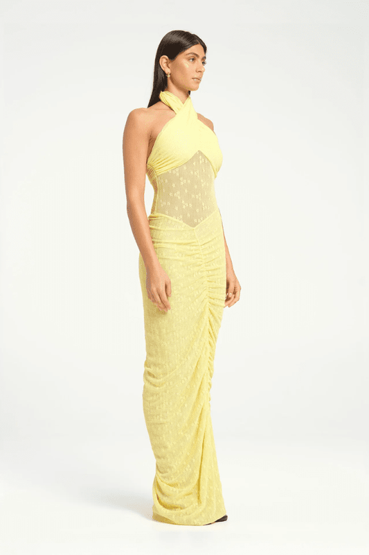 Hudson Lace Maxi Dress Butter by Benni, elegant stretch lace dress with twist halter neck, ruched seams, and sheer waist panel for a bold evening look.