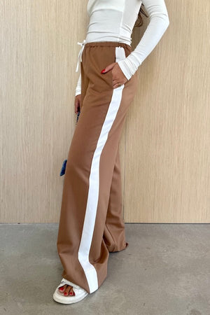 Denver Pant Tan by Sneaky Link, relaxed fit with elastic waist, contrast side stripe, and drawstring for a sporty look. Made from polyester blend. Cold hand wash. Size down if between sizes.