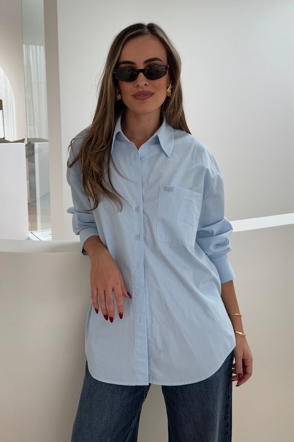 Boston Shirt Light Blue by Sneaky Link — Timeless oversized button-up in crisp cotton poplin with signature snake embroidery on the pocket. Classic, fresh, and versatile.