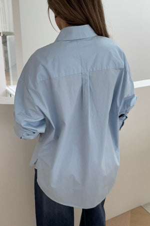 Boston Shirt Light Blue by Sneaky Link — Timeless oversized button-up in crisp cotton poplin with signature snake embroidery on the pocket. Classic, fresh, and versatile.