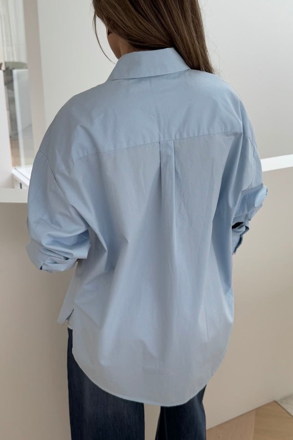 Boston Shirt Light Blue by Sneaky Link — Timeless oversized button-up in crisp cotton poplin with signature snake embroidery on the pocket. Classic, fresh, and versatile.