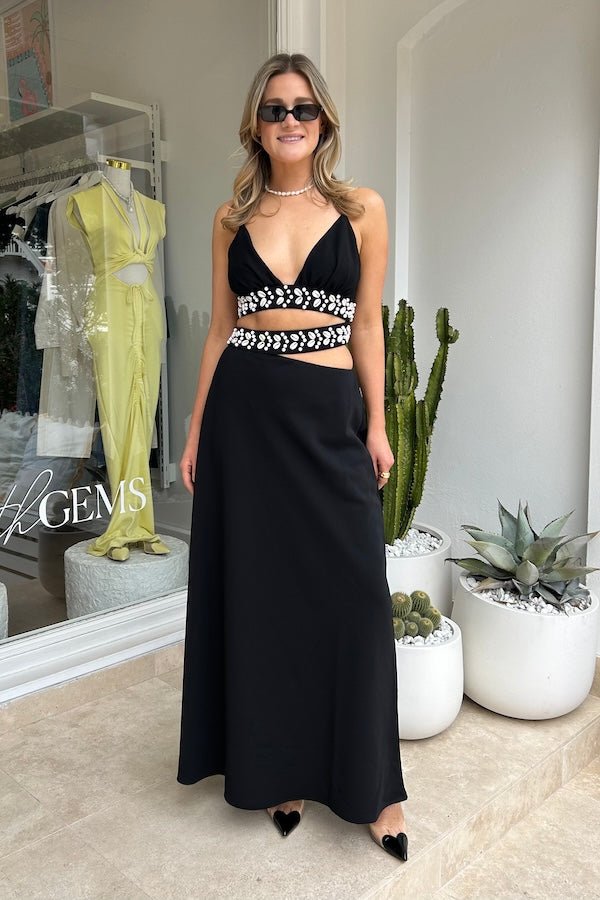 La Playa Maxi Dress Noir by The Wolf Gang – Maxi dress with cowrie shell cutouts, adjustable tie, and luxe gold clasp closure.