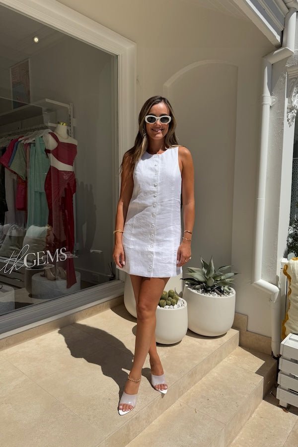 Mia Mini Dress White by Sneaky Link – A trendy, breathable linen dress with a high scoop neckline and button front, perfect for effortless summer days.