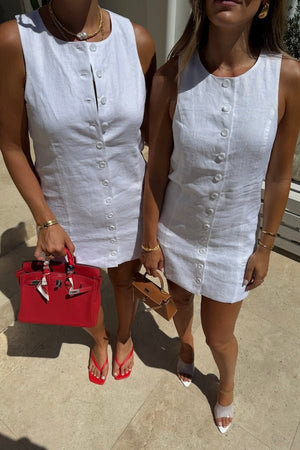 Mia Mini Dress White by Sneaky Link – A trendy, breathable linen dress with a high scoop neckline and button front, perfect for effortless summer days.