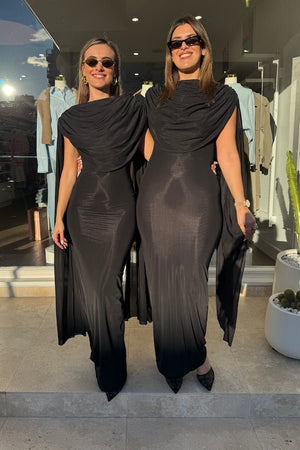 Batista Basalto by Maygel Coronel – An elegant long dress with a cowl scoop neckline, flowing shoulder sashes, and a sleek column silhouette, perfect for sophisticated evening events and making a timeless, statuesque statement.