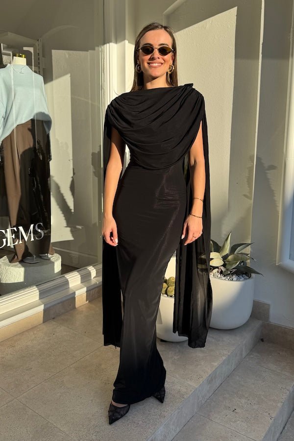 Batista Basalto by Maygel Coronel – An elegant long dress with a cowl scoop neckline, flowing shoulder sashes, and a sleek column silhouette, perfect for sophisticated evening events and making a timeless, statuesque statement.