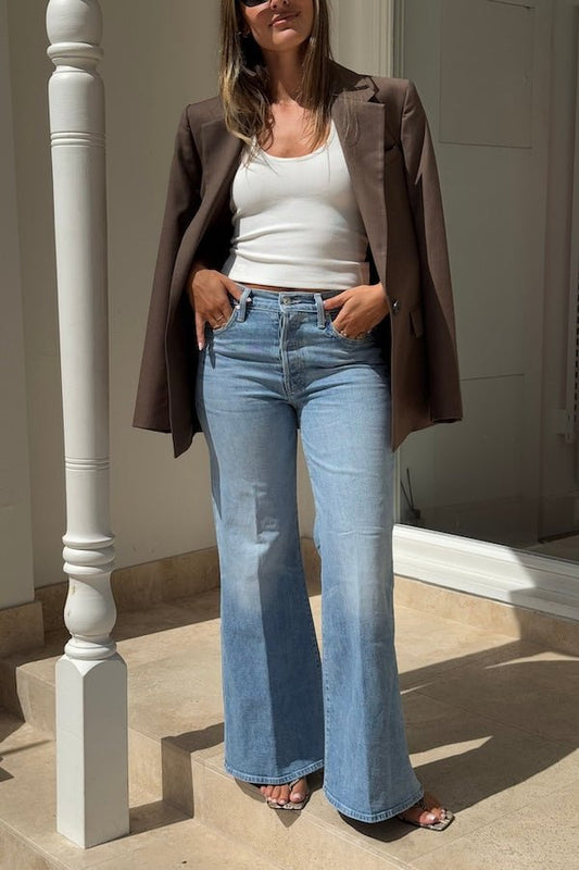 The Tomcat Roller Skimp Puzzled by MOTHER, trendy high-waisted wide-leg jeans with a button fly and light blue wash. Perfect for a relaxed, stylish look with whiskering and fading at the knees.