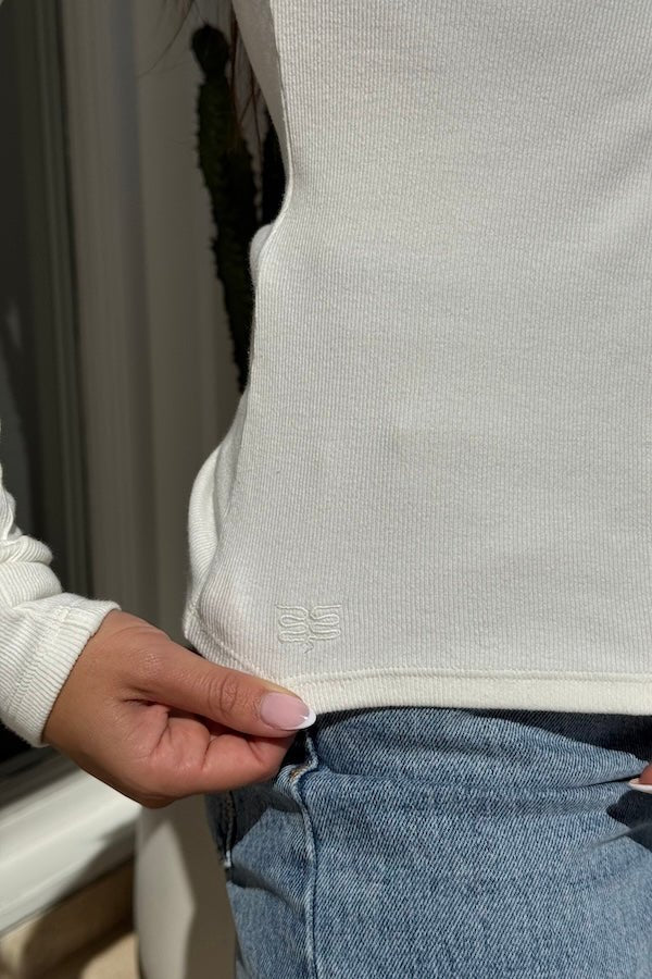 Lottie Long Sleeve Top White by Sneaky Link – Soft cotton blend with scoop neckline and snap button detail. Perfect for chic layering and viral winter style.