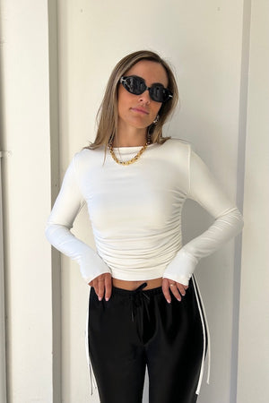 Lumi Cropped Top White by Sneaky Link – Soft bamboo blend long sleeve with adjustable tie sides and thumbholes, offering versatile cropped or full-length styling for effortless sophistication.