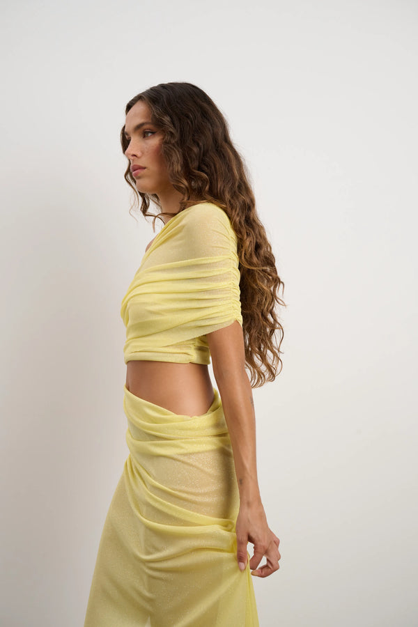 Lara Dress Yellow by DŽO – a one-shoulder gown with ruched wrap and slit. Perfect for bold evening styling.