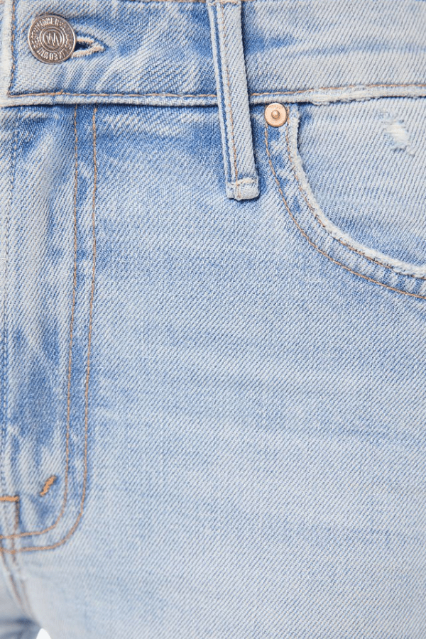 The image depicts a person from the mid-torso down, showcasing a fashion outfit consisting of a sleeveless white top with gold buttons, light blue denim jeans, gold bracelets on both wrists, and white high-heeled shoes. The setting appears to be indoors or a covered outdoor area with a white pillar and a door frame visible in the background. The color scheme is primarily white, light blue, and gold, creating a bright and soft aesthetic.