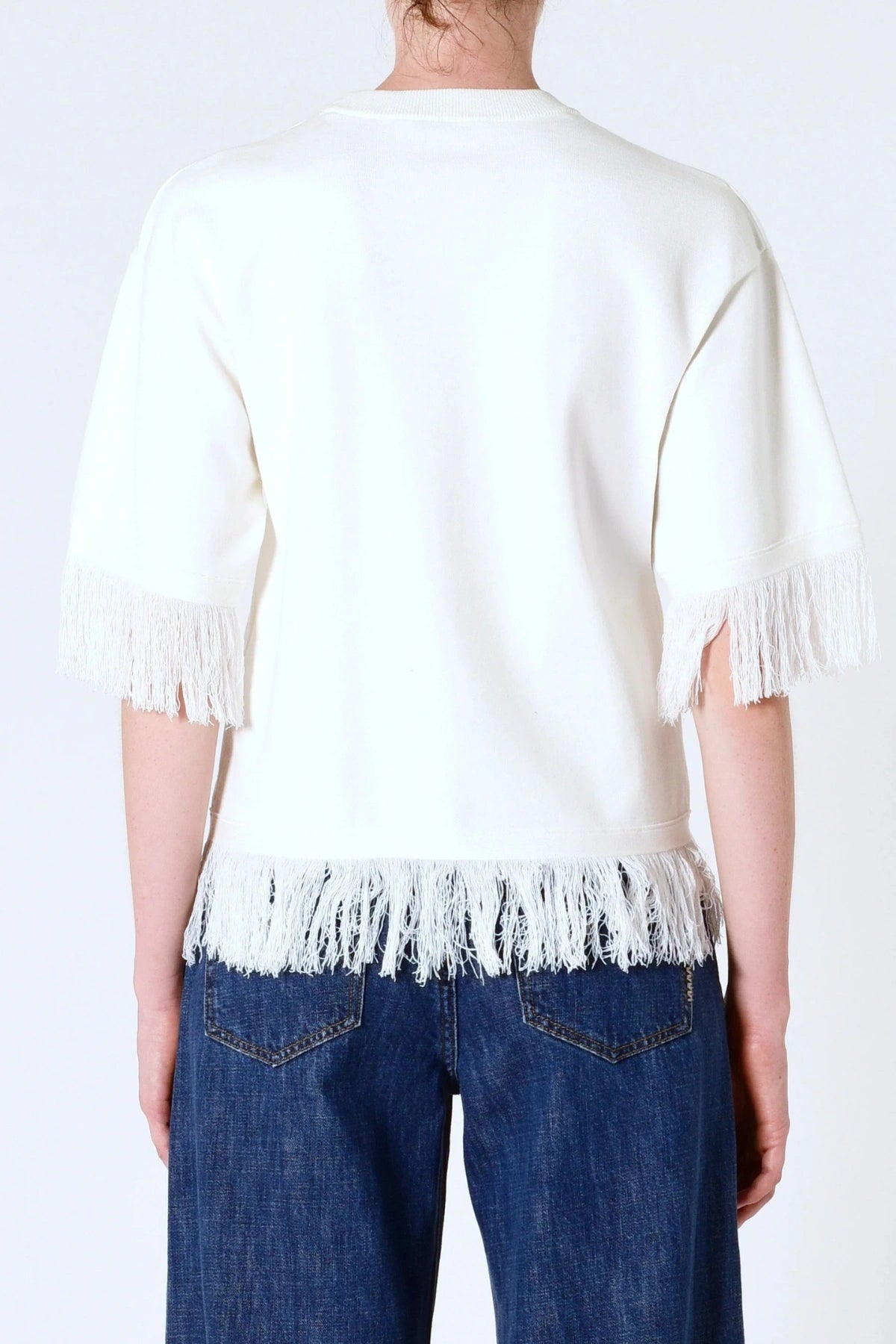 Marrakech Fringe Knit in White by Neuw Denim, a sleeveless relaxed knit with fringe hem. Perfect for layering with denim or linen.
