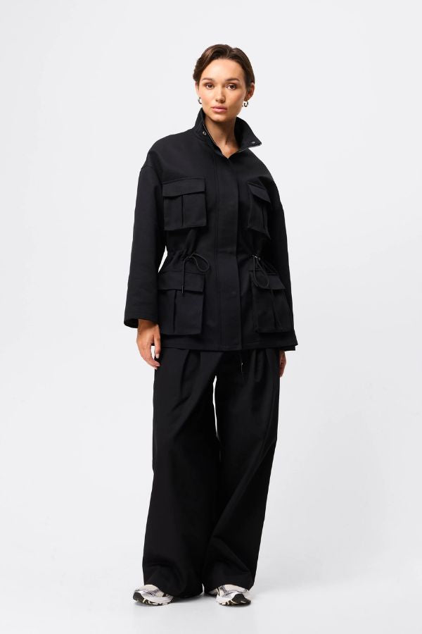 Mossman My Muse Anorak in Black, a modern utility jacket featuring oversized flap pockets, adjustable drawstring waist, and a concealed zip front for an elevated off-duty look. 4 