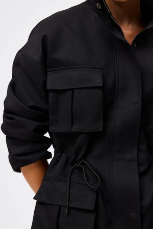 Mossman My Muse Anorak in Black, a modern utility jacket featuring oversized flap pockets, adjustable drawstring waist, and a concealed zip front for an elevated off-duty look.